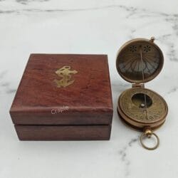 Antique brass pocket sundial compass shown open next to its closed wooden box which features a brass anchor inlay.