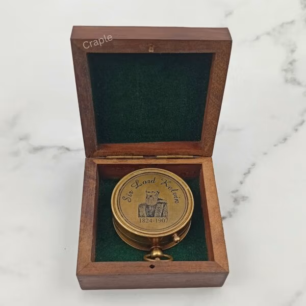 The back of the antique brass pocket compass, engraved with 'Made for Royal Navy, London', resting in its wooden box.