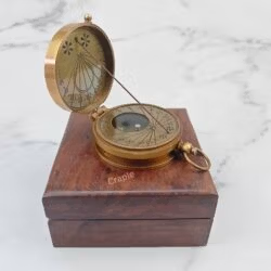 Antique brass string sundial compass perched open on its closed wooden box, showcasing its vintage design.