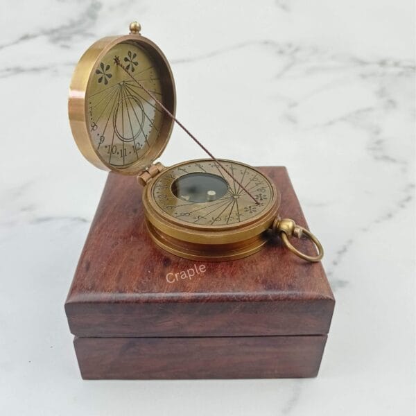 Antique Brass String 2 Inch Compass-6 Antique brass string sundial compass perched open on its closed wooden box, showcasing its vintage design.