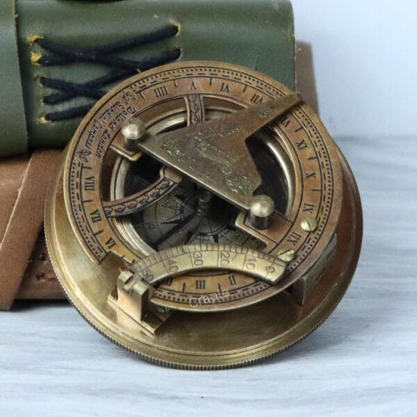Top-down view of the antique brass sundial compass with its gnomon raised over the Roman numeral dial