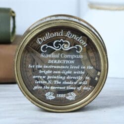 Close-up of the glass lid of the Dollond London compass, showing the vintage 'DIRECTION' instructions from 1885.