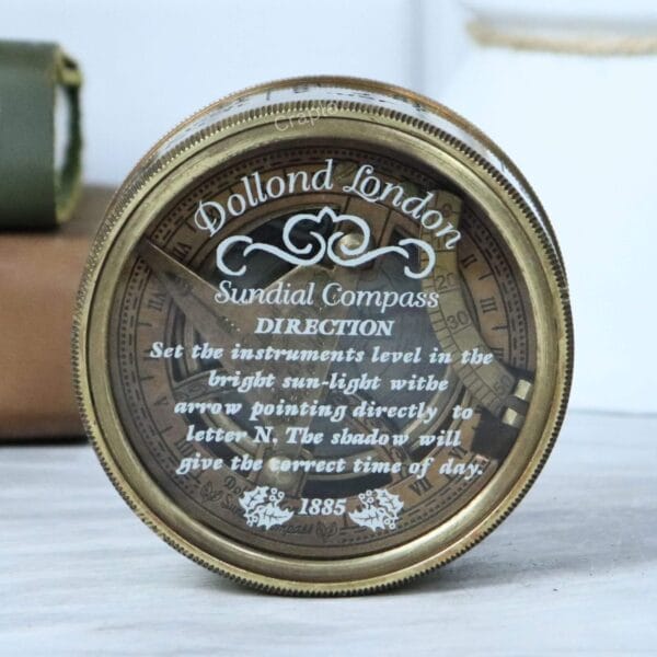 Close-up of the glass lid of the Dollond London compass, showing the vintage 'DIRECTION' instructions from 1885.