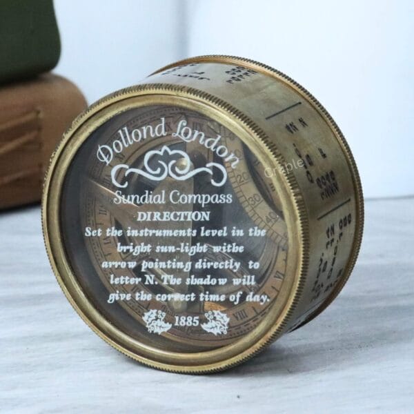 The closed brass sundial compass from an angle, showcasing the perpetual calendar engravings on the side of the casing