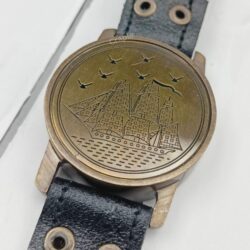 Detailed close-up of the embossed sailing ship and birds on the brass lid of the wrist compass.