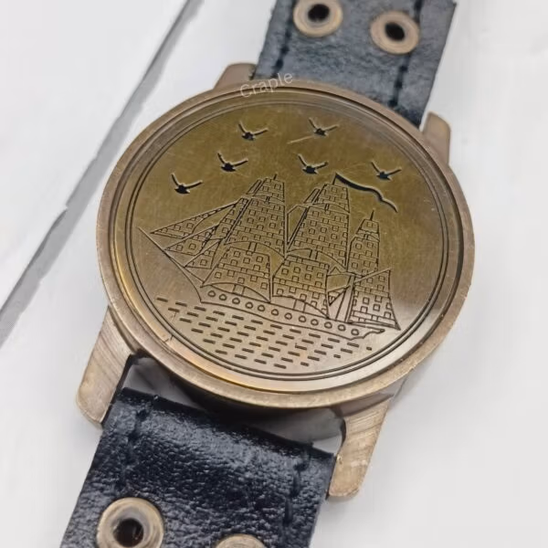 Detailed close-up of the embossed sailing ship and birds on the brass lid of the wrist compass.