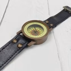 Side view of the steampunk-style brass wrist compass, highlighting the case and the connection to the leather strap.