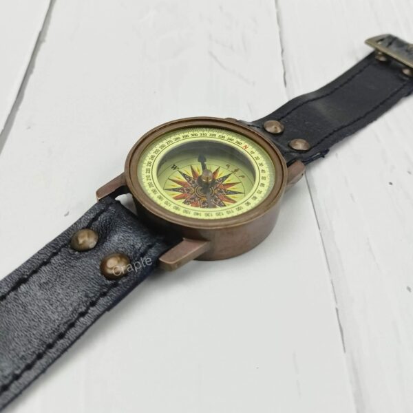 Side view of the steampunk-style brass wrist compass, highlighting the case and the connection to the leather strap.