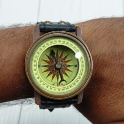The antique brass and leather wrist compass being worn on a person's arm to show its size.