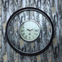 Industrial-style wall clock crafted from a bicycle rim and tire, with a vintage Roman numeral clock at the center.
