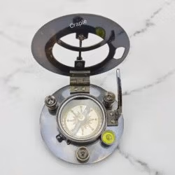 Angled view of the open black brass sundial compass, showing the hinge mechanism and internal details.