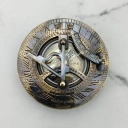 Top-down view of the black antique sundial compass face, detailing the gnomon, latitude arc, and Roman numerals.