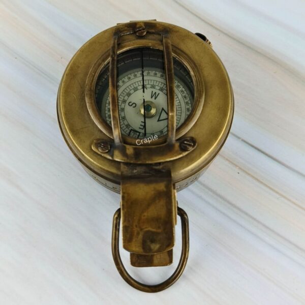 Top-down view of the closed WWII military-style brass compass, with the compass dial visible through the top glass.