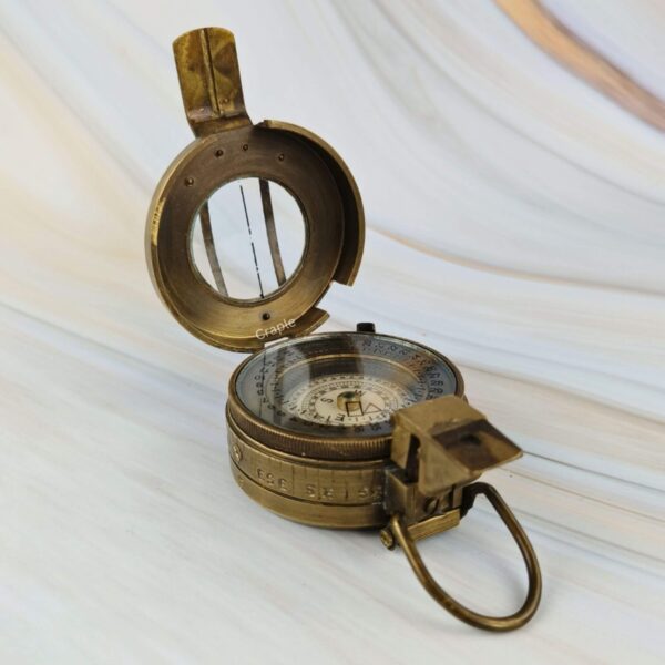 Open brass prismatic compass highlighting the lid with its sighting line and the folding prism for taking bearings.