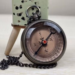 Engraved brass pocket compass for a son, featuring a black antique finish and a matching chain on a wooden surface.