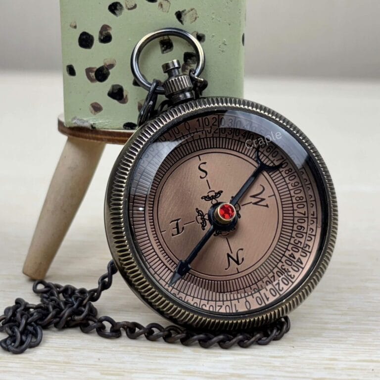 Engraved brass pocket compass for a son, featuring a black antique finish and a matching chain on a wooden surface.