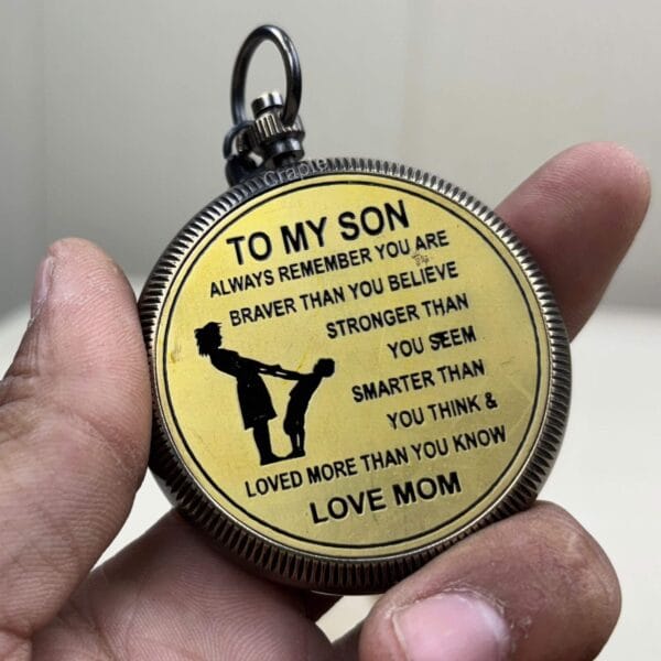 Close-up of the back of a brass compass showing the engraved message "To My Son... Love Mom".