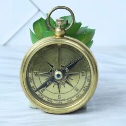 A vintage-style open-face pocket compass made of shiny brass, featuring a classic compass rose dial.