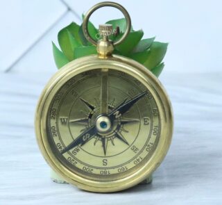 A vintage-style open-face pocket compass made of shiny brass, featuring a classic compass rose dial.