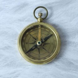 Angled view of the classic brass compass, highlighting the detailed dial and the floating magnetic needle.