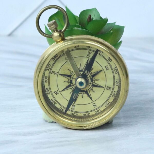 Classic Open Face Pocket Compass-7 A three-quarter view of the open-face brass pocket compass, displaying its antique-style dial and top loop.
