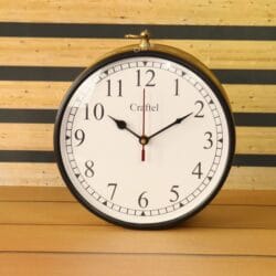 Front view of a round station clock with a golden finish, a white face, and black Arabic numerals.