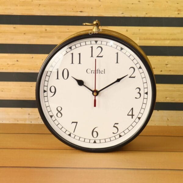 Front view of a round station clock with a golden finish, a white face, and black Arabic numerals.