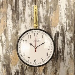 Front view of one side of the hanging, two-faced golden station clock, showing the clear dial.