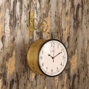 Vintage double-sided station clock with an embossed golden casing, hanging from a decorative wall bracket.