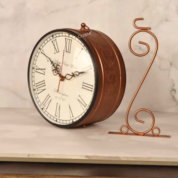 Double-sided vintage station clock displayed on a decorative brass-coated tabletop stand with a swirl design.