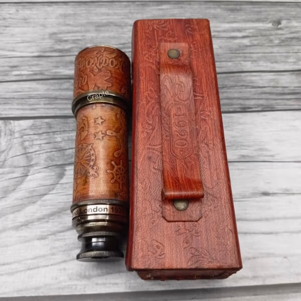 Collapsible brass and leather telescope shown beside its embossed red leather travel case, highlighting the portability.