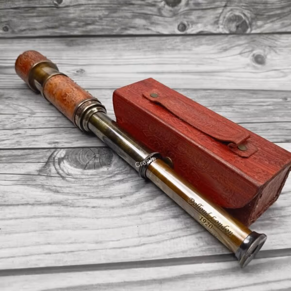 Nautical-style extendable brass telescope with a detailed embossed leather grip, shown with its red case.