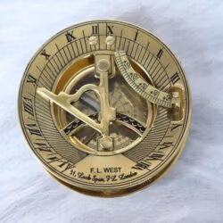 Top-down view of a shiny brass F.L. West London sundial compass showing the gnomon, latitude scale, and Roman numerals.