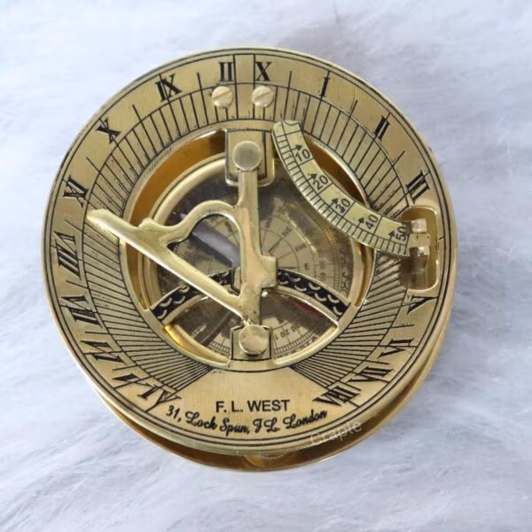 Top-down view of a shiny brass F.L. West London sundial compass showing the gnomon, latitude scale, and Roman numerals.