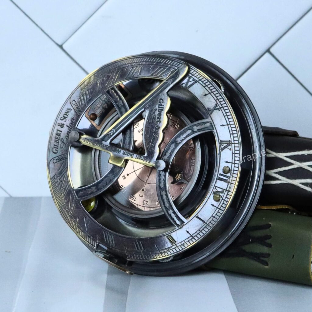 Antique brass sundial compass by Gilbert & Sons with a black finish, featuring a folding gnomon and a detailed compass dial.