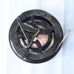 Top-down view of the Gilbert & Sons sundial, showing the internal compass with cardinal points and needle.
