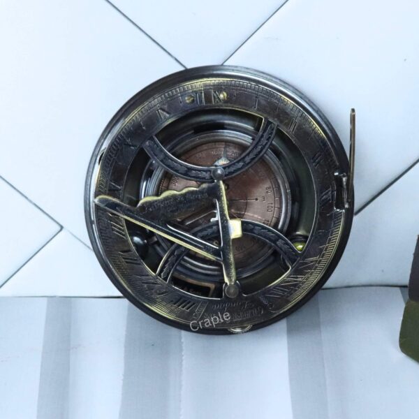 Angled view of the antique-style brass sundial compass, highlighting the side lever and black finish.