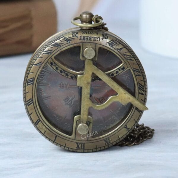 Front view of a Gilbert & Sons antique brass pocket sundial compass, showing the foldable gnomon and compass face.