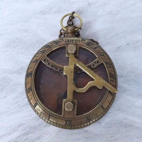 Top-down view of the antique brass sundial compass face, detailing the gnomon, cardinal points, and "Gilbert" engraving.