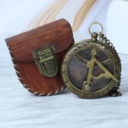 The antique brass pocket sundial shown next to its open, hand-stitched brown leather carrying pouch.