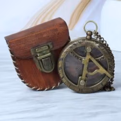 The antique brass pocket sundial shown next to its open, hand-stitched brown leather carrying pouch.