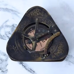 Top-down view of the antique brass sundial lid, showing the foldable gnomon, latitude arc, and engraved details.