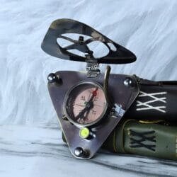 The antique-style triangular brass compass opened and displayed next to vintage-style books.