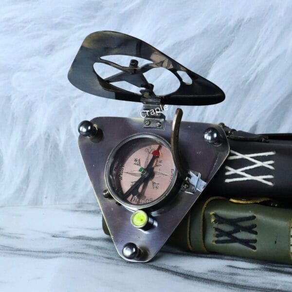 The antique-style triangular brass compass opened and displayed next to vintage-style books.