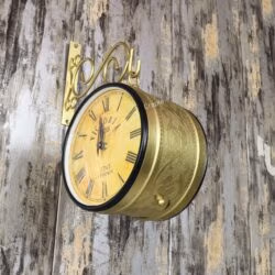 Angled view of the wall-mounted golden railway clock, showing its depth and dual-face design.