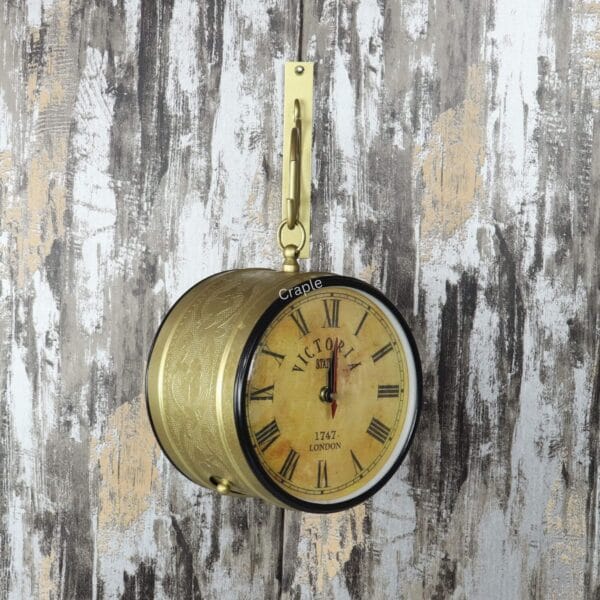 Front view of the golden Victoria Station clock hanging from its decorative wall-mounted bracket.