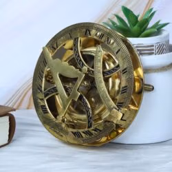 Handcrafted brass sundial compass with a shiny finish, displayed as a decorative piece next to a succulent plant.