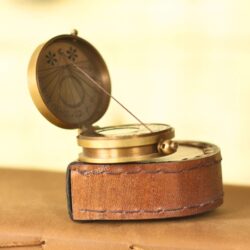 Side view of the handcrafted pocket compass, showing its genuine stitched leather casing and brass body.