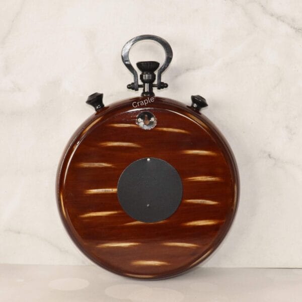 The back of the stopwatch-style wall clock, showcasing the beautiful brown wood grain finish and hanging mechanism.