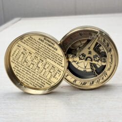 Open brass sundial compass showing the sundial face on one side and a perpetual calendar inside the lid.
